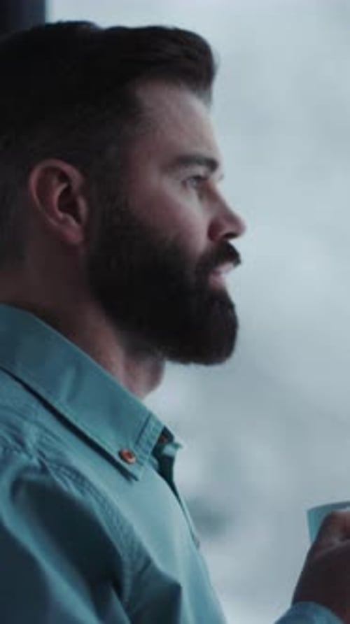 Bearded Man Drinking From Mug Looks Out Window