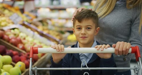 Authentic close up shot of happy mother and son with shopping cart are choosing food products to b