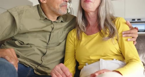 Loving Senior Couple Holding Hands on Couch Indoors