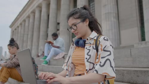 Girl Studying Online with Laptop on Stairs Outside the University