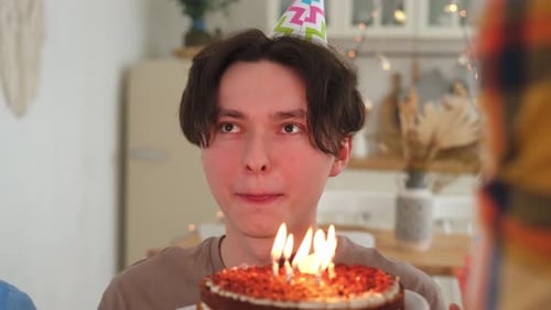 Young Man Blows Out Birthday Cake Candles