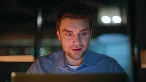 Un travailleur indépendant souriant navigue sur un ordinateur et se sentant satisfait, projet nocturne, gros plan