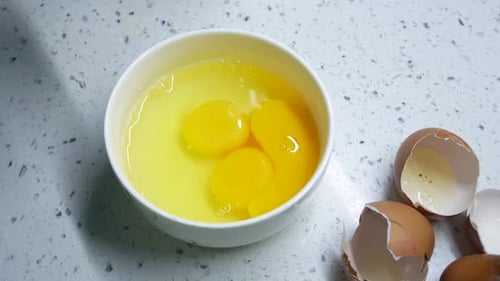 Cracking Eggs Into Bowl on Countertop
