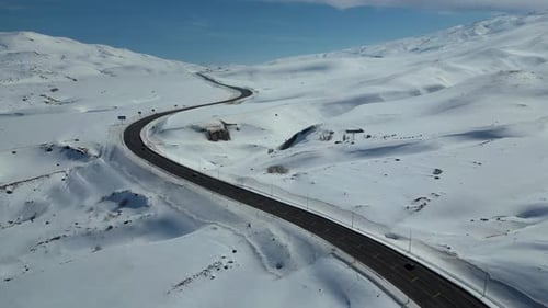 Luftaufnahme der kurvenreichen Autobahn durch schneebedeckte Berge