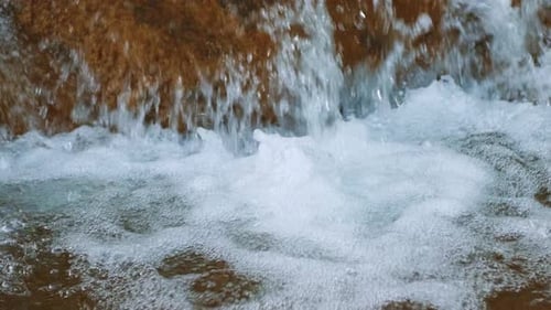 Nahaufnahme eines natürlichen Wasserfalls, der auf Felsen plätschert