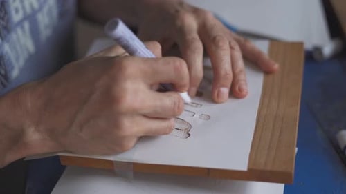 Artiste utilisant un pochoir pour écrire un message personnel sur du bois