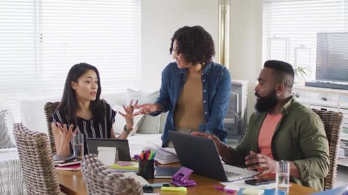 Divers amis masculins et féminins utilisant un ordinateur portable et parlant, travaillant à la maison, Ralenti