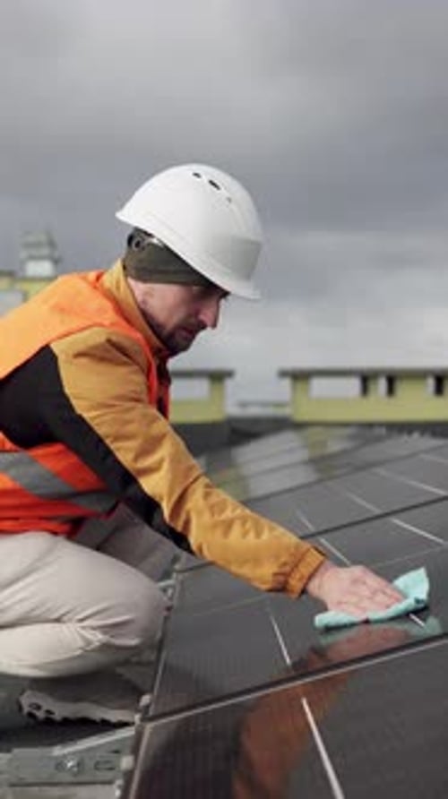 Worker cleaning solar panels, emphasizing maintenance and energy efficiency.