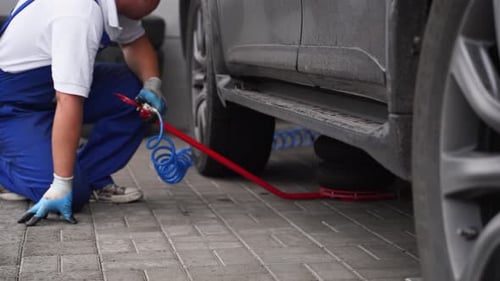 Auto Mechanic Uses Air Jack to Lift Vehicle Removes Tire with Pneumatic Impact Wrench in Garage
