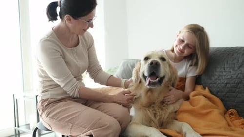 Woman and Girl Petting Golden Retriever Dog at Home