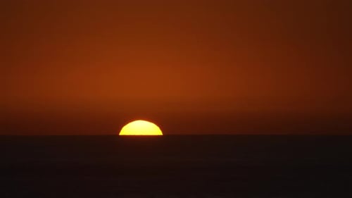 Golden sun setting over a dark ocean with a beautiful orange lit sky
