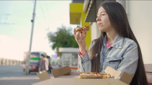 Young Woman Enjoys Pizza in the City