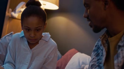 Father and Daughter Reading Together on Bed at Night