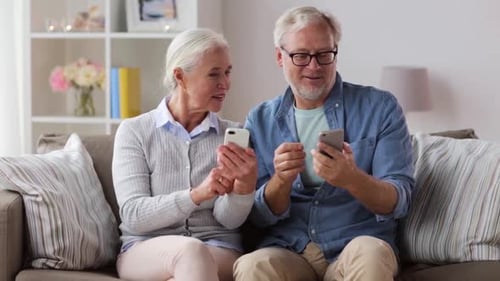 Senior Couple Looking at Smartphones Sitting on Couch