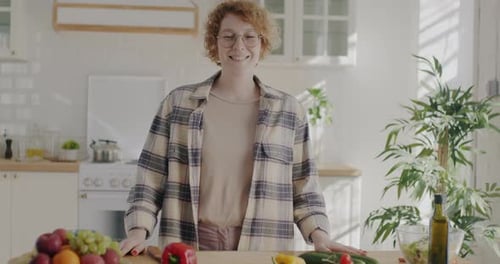 Woman Smiles with Vegetables in Bright Kitchen