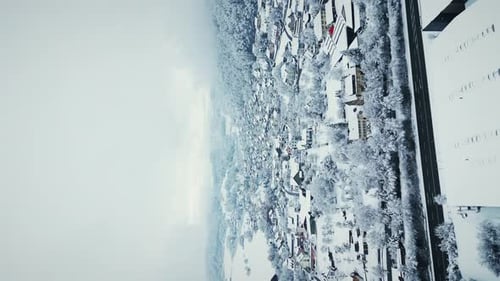 Winterszene mit Dorf, umgeben von Pinienwäldern mit fallendem Schnee