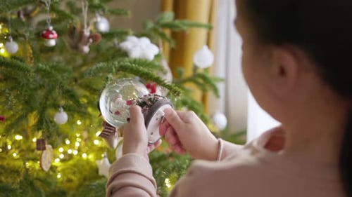 A Girl is Turning the Key of the Christmas Globe - Close Up