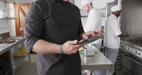 Caucasian male chef using tablet in kitchen, slow motion
