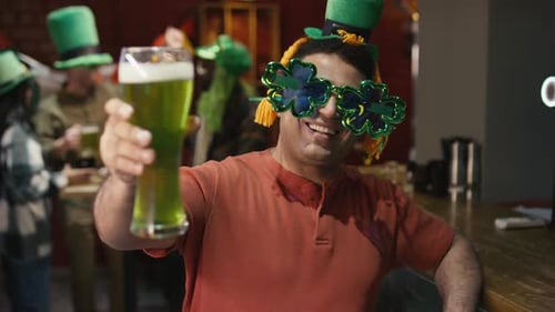 Portrait of Happy Man in Glasses Offering Green Beer on St Patricks Day