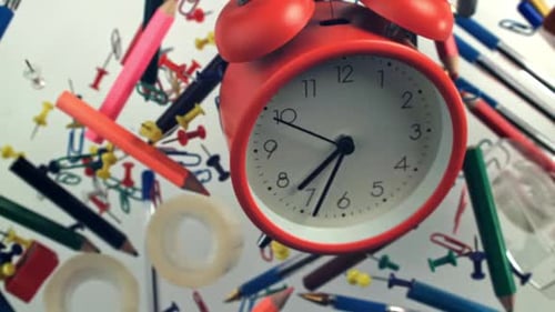 An Alarm Clock with Various School Supplies Flies Up and Falls Filmed on a Highspeed Camera at 1000