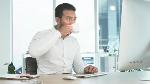 Business man working on a computer and drinking coffee in an office