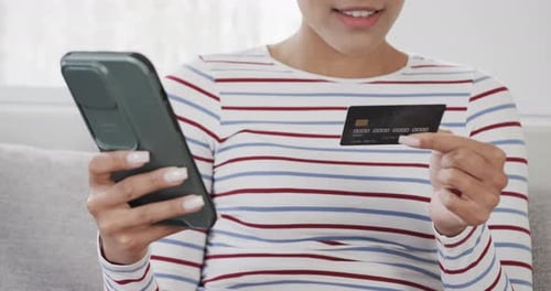 Person Holds Phone and Credit Card Indoors