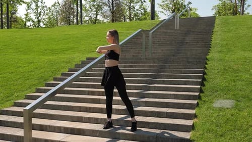 A Slender Young Woman Trains Outdoors in the Park on the Steps in the Morning
