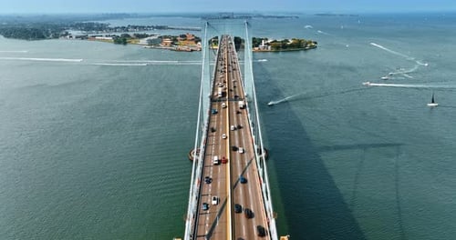 Flying along the six lane road on the Throgs Neck Bridge. Multiple boats float over the East River.
