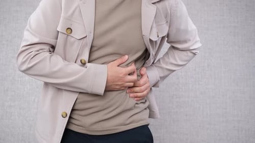 Adult holding abdomen in discomfort close up