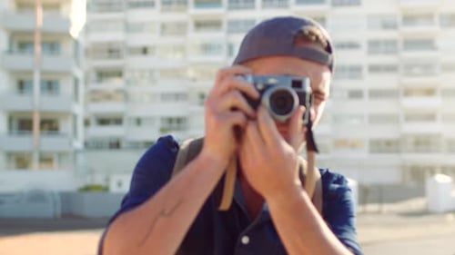 A young talented male photographer taking pictures outdoors in the city