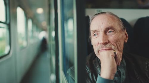 Portrait d'un homme âgé regardant par la fenêtre d'un coupé alors qu'il voyageait en train