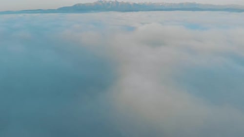 high mountains slowly revealed above thick layer of clouds with a blue sky just after sunrise