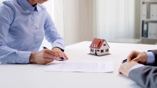Businessman handing over house keys to a woman after signing real estate contract