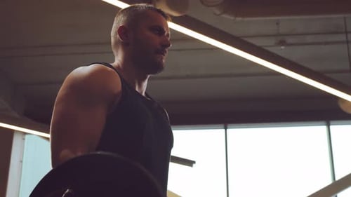 Sportlicher gutaussehender männlicher Sportler, der im Fitnessstudio mit Langhantel arbeitet Starker und gesunder Bodybuilder