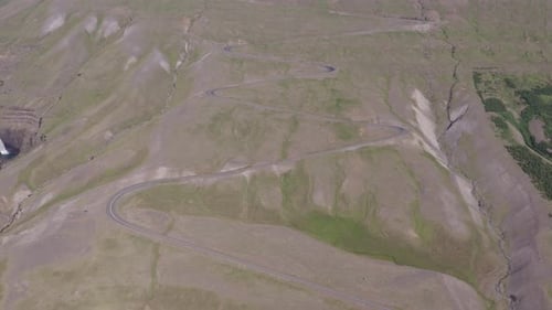 Meandering gravel road going up steep mountain in Iceland, aerial