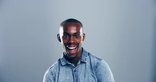 4k video footage of a young man laughing against a grey studio background
