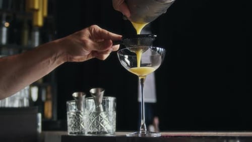 Bartender Pouring Cocktail Into Glass Through Strainer