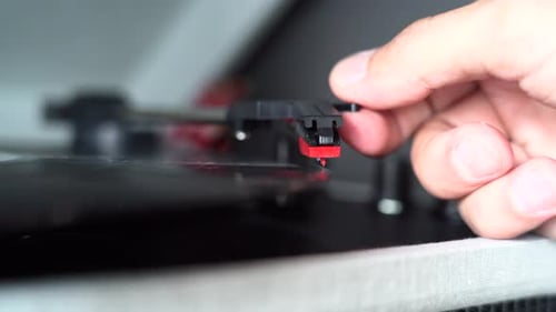 Moving the head of a record player to start playing an old vinyl. Needle close up shot