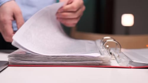 Office Worker Browsing Through Documents in a Binder
