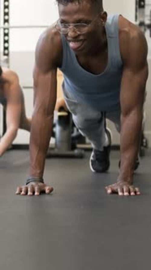 Man Does Plank with Smile in Modern Gym