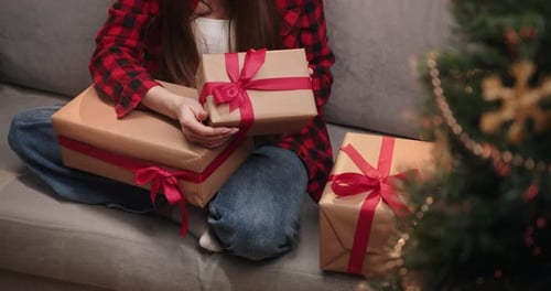 Woman with Presents on Couch next to Christmas Tree