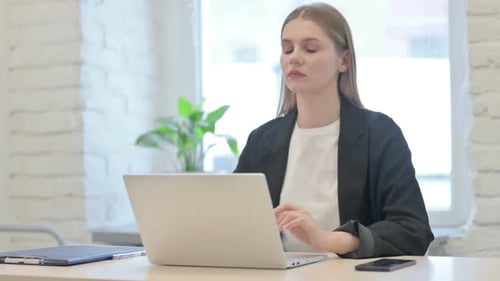 Young Adult Massages Stiff Neck at Desk