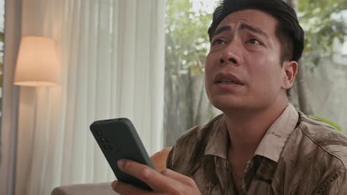 Worried Young Adult Using Smartphone Indoors