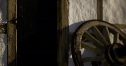 Rustic Wooden Wheel Next to an Old Door Reveals Village Charm at Sunset