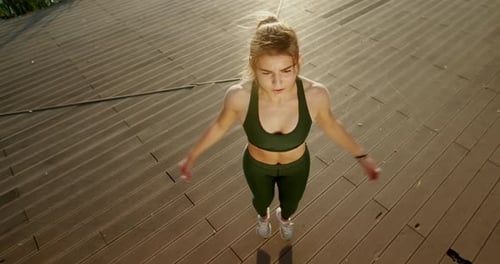 Female Athlete Jumping on Wooden Embankment