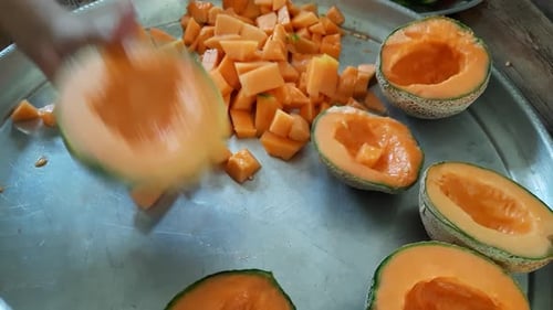 L'homme utilise un couteau pour fendre le melon orange, le melon musqué, le cantaloup sur une plaque d'acier, Muskmelon Ju