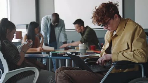 Young Businessman in Wheelchair Working on Laptop in Open Space Office