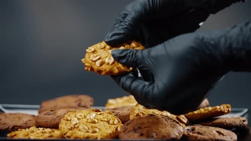 Close Up on a Black and Blue Background Flat Plate with Cookie Cookies Built in a Pyramid a Female