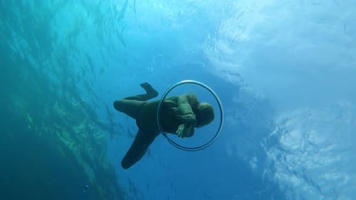Beautiful female diver swims gracefully through a bubble ring underwater