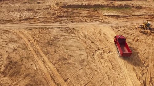 Red Dump Truck Driving on Construction Site Aerial